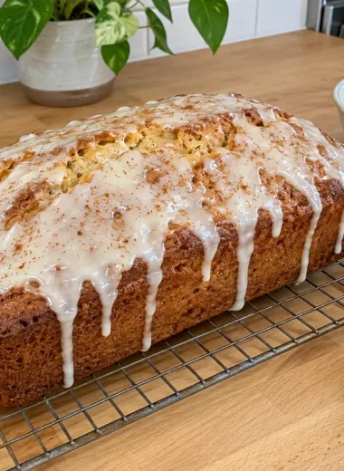 Eggnog Bread Recipe - a glazed eggnog loaf on a wire rack with rum glaze dripping down the sides and a sprinkle of nutmeg
