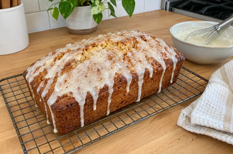 Eggnog Bread Recipe - a glazed eggnog loaf on a wire rack with rum glaze dripping down the sides and a sprinkle of nutmeg