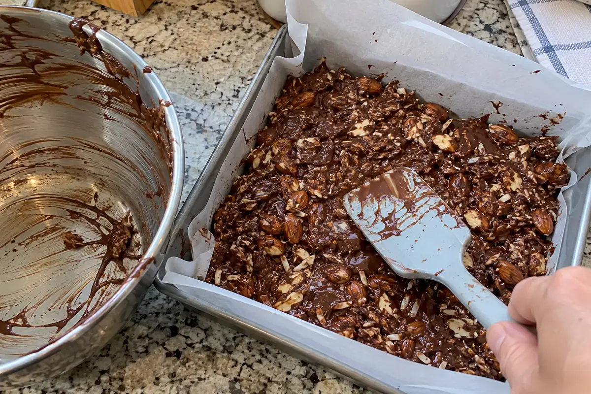 Pressing the chocolate almond mixture into a lined pan to make sugar free candy bars