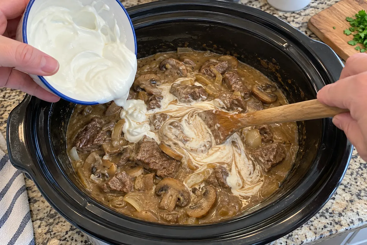 Crockpot Beef Stroganoff – stirring tempered sour cream into the beef and mushroom sauce in the slow cooker