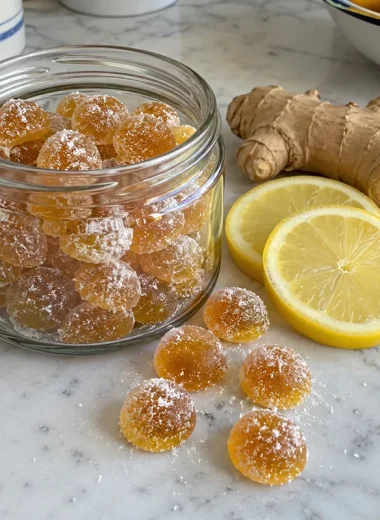Honey Lemon Ginger Tea Bombs - glossy golden honey drops in a small glass jar with lemon slices and fresh ginger